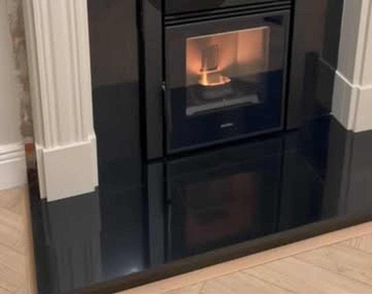 An Elcofire pellet stove fitted by Stove Fit into a cream fireplace surround, lit