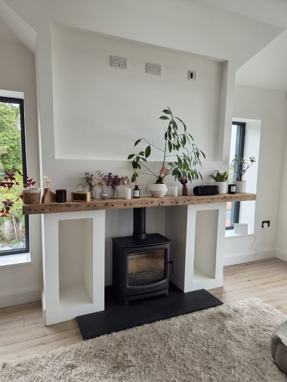 A stove set into a plastered chimney breast with a reclaimed timber beam and slate hearth, built and fitted by Stove Fit